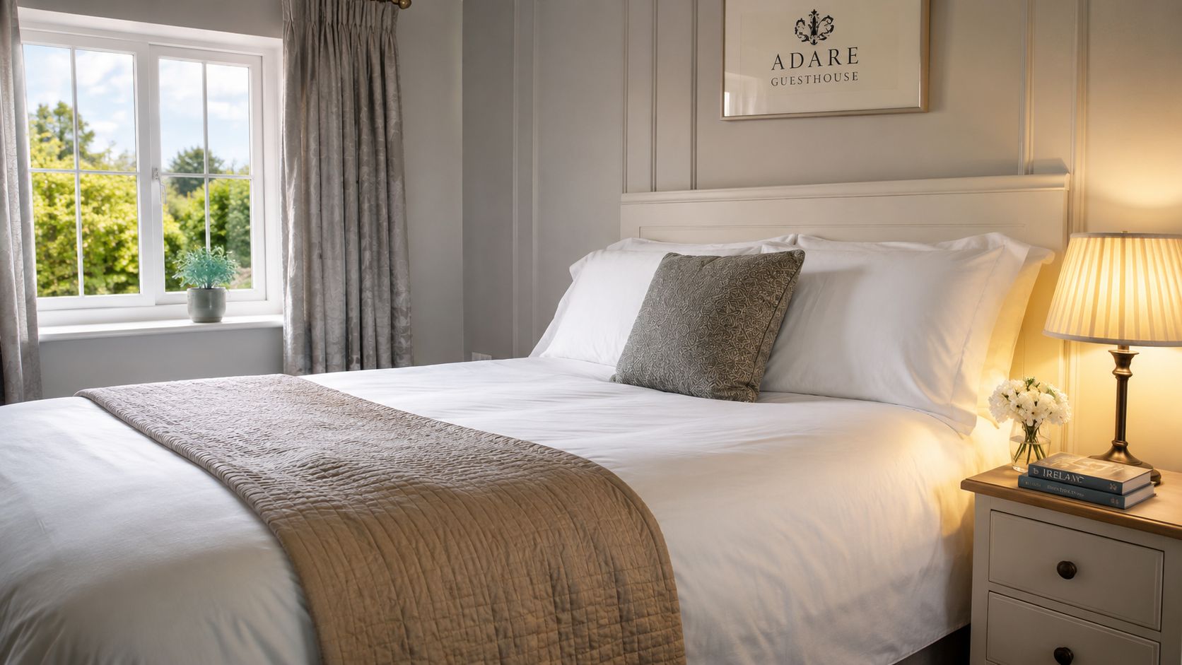 A cozy bedroom in Adare Guesthouse with a neat bed, elegant lamp, and a bright window view.